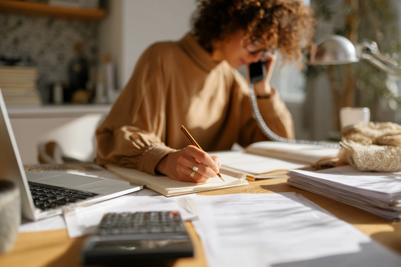 Secrétaire en poste, en train de répondre au téléphone et de prendre des notes – formation Secrétariat Adalia