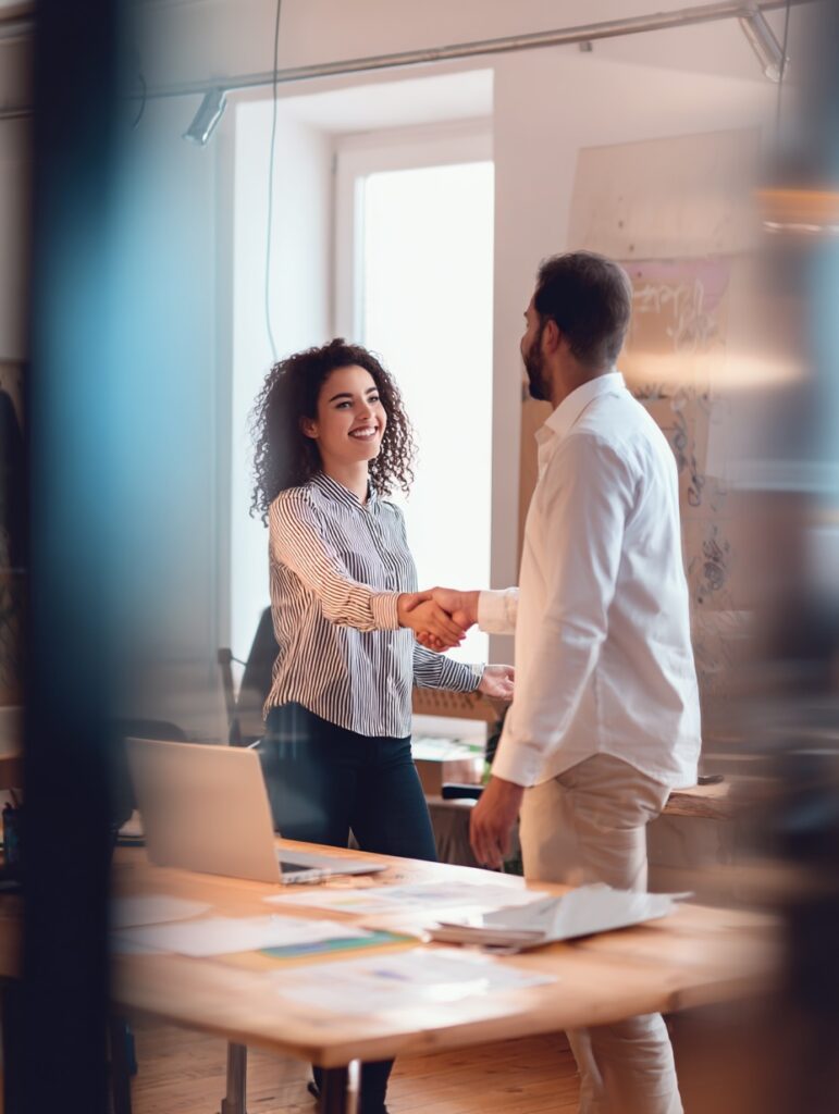 Jeune assistante RH accueillant un salarié dans un bureau professionnel, illustration des métiers des ressources humaines.