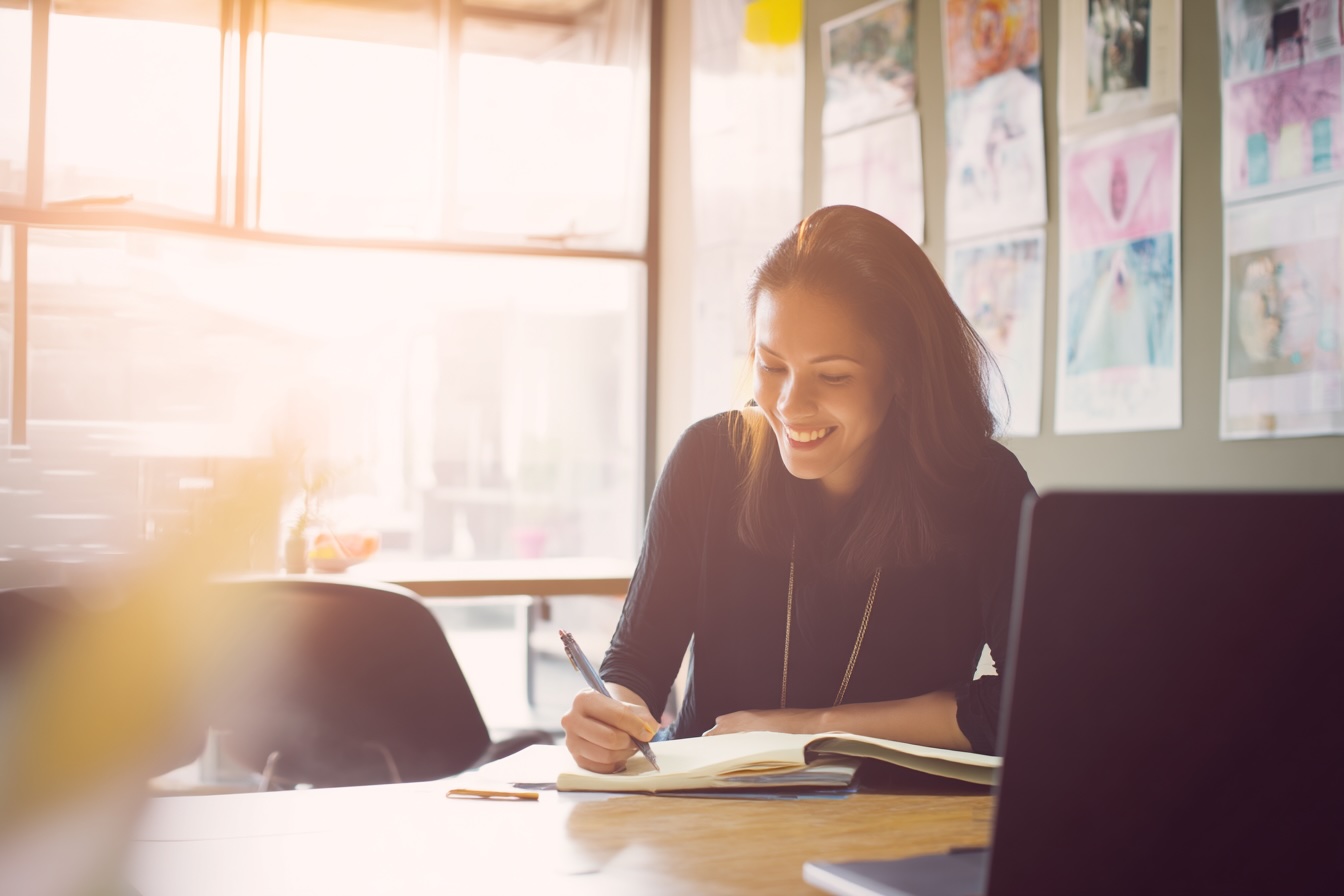 Femme en formation professionnelle, concentrée et souriante, dans un environnement lumineux